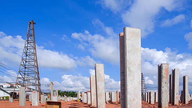 istock Many precast concrete piles foundation structure on the ground with pile driver machine in industrial factory building construction site against clouds blue sky background 2212769510