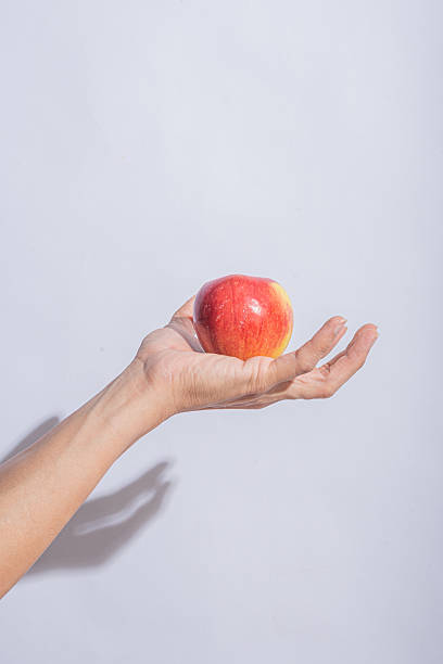 istock A red apple resting on an open palm against a clean light gray background, emphasizing the fruit's fresh texture and vibrant color 2212769517