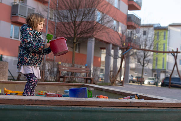 istock A Child Engaged in Play within a Sandbox using a Bucket by an Apartment Complex 2212772023
