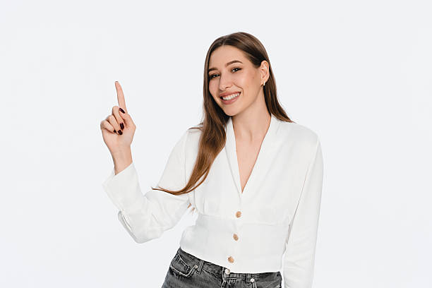 istock Confident Woman Smiling and Pointing Up on a White Background 2212772471