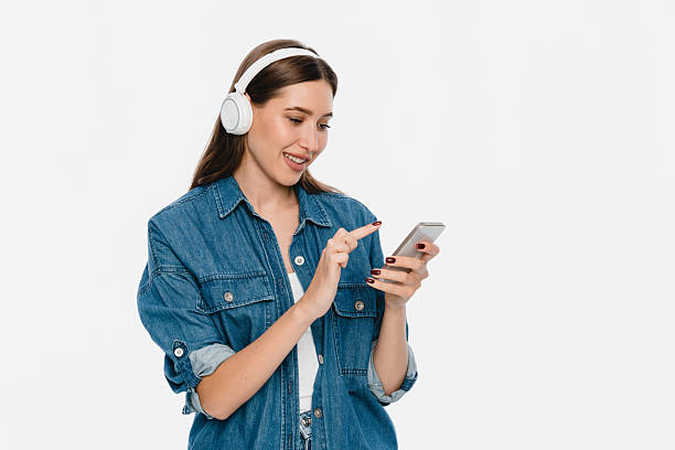 istock Woman Enjoying Music While Browsing Smartphone in Casual Denim Attire 2212772796