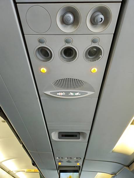 The overhead control panel inside an airplane cabin, featuring reading lights, air vents, and call buttons above passenger seats.