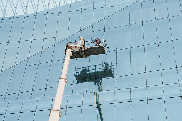istock Cleaner worker using a cherry picker to clean a glas facade of a contemporary office building 2212774281