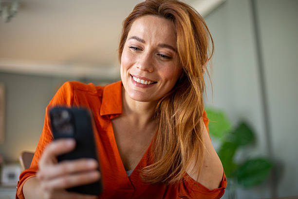 istock Smiling woman using smartphone at home: browsing internet and social media 2212775193