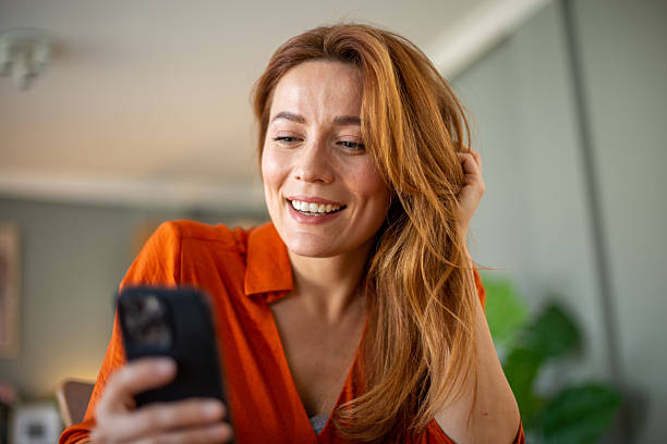 istock Smiling woman using smartphone at home reading good news 2212776301