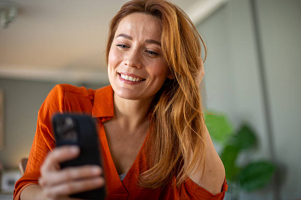 istock Smiling woman using smartphone at home reading good news 2212776310