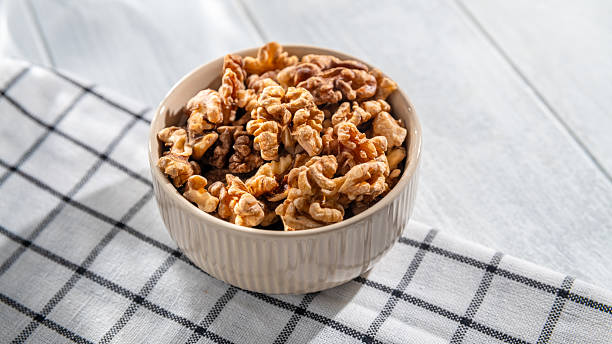istock Shelled walnuts resting in a bowl on a checkered tablecloth create an inviting scene, highlighting a nutritious and delicious snack perfect for any healthy lifestyle 2212777181