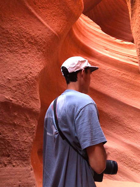 Photographer explores sandstone slot canyon, Utah