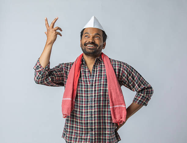 Portrait of smiling mid adult farmer wearing topi and scarf gesturing and looking away while standing on white background