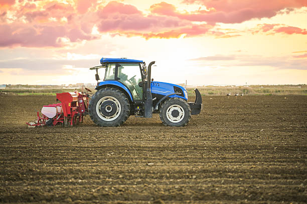 istock Farmer sowing seeds with tractor and seed drill at sunset in rural field 2212782569