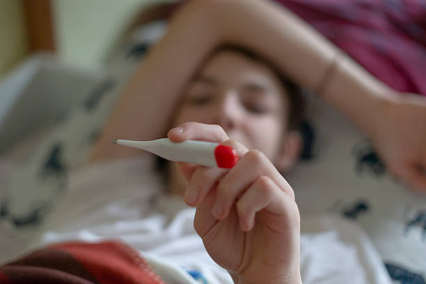 istock A Sick Person Resting in Bed, Surrounded by Blankets and a Thermometer 2212782963