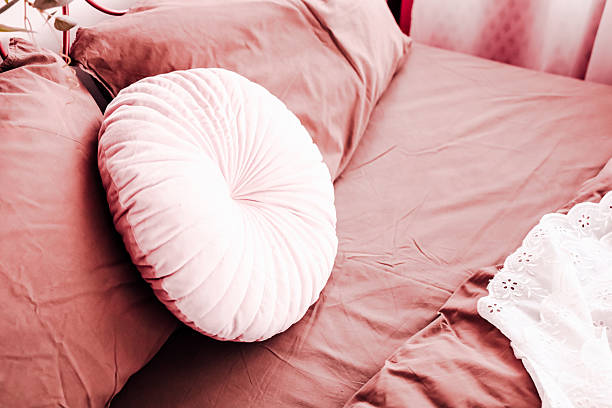 istock Cozy bedroom with a decorative round pillow on a brown bedspread and delicate lace 2212783737