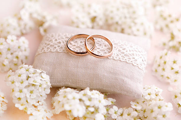 Gold wedding rings on a cushion with lace and white flowers