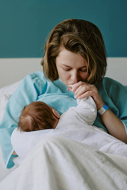 istock Mother Kissing Infant While Holding in Bed with Blue Blanket 2212786224
