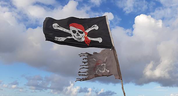 the black pirate flag with skull symbol waving on the beach near the ocean.