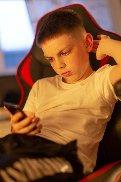 istock A young boy is focused on his smartphone while sitting in a gaming chair 2212795861