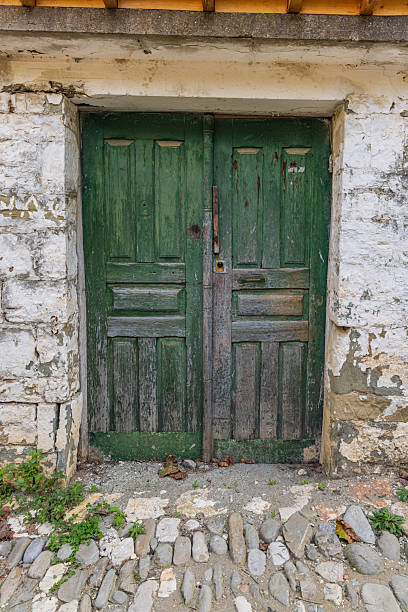 istock Weathered green wooden doors in an old stucco building. 2212798139