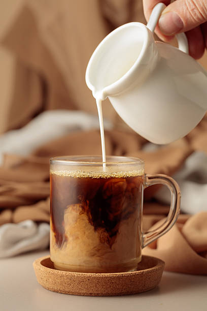 istock Pouring cream in black coffee. 2212799087