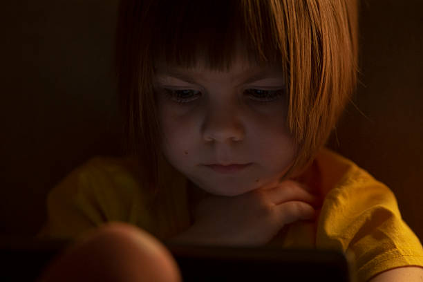 istock A Young Child Deeply Engrossed in a Screen Evening Glow Sparks Curiosity 2212800398