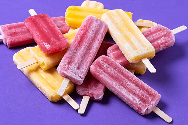 istock Red strawberry popsicles and yellow popsicles on purple background 2212801875