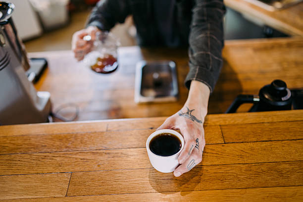 A Hispanic man works skillfully in an urban cafe preparing a pour over style drip coffee.