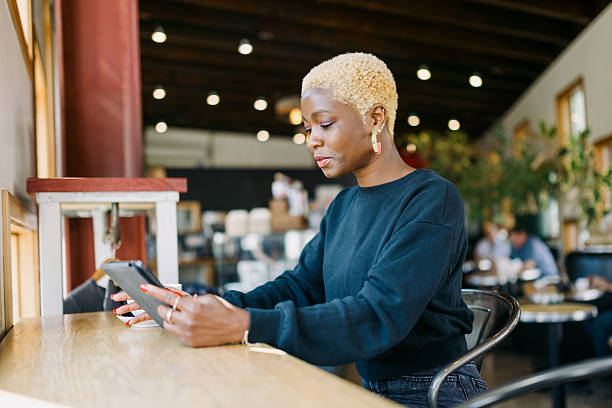 istock Woman Working on Digital Tablet In Bright Urban Cafe 2212802130