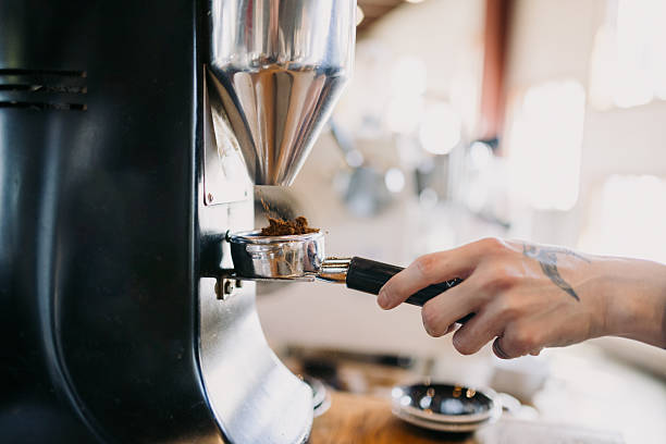 A Hispanic man works skillfully pulling shots of single origin espresso for a latte drink in a small urban cafe. He grinds fresh beans for the drink.  Shot in Portland, Oregon.