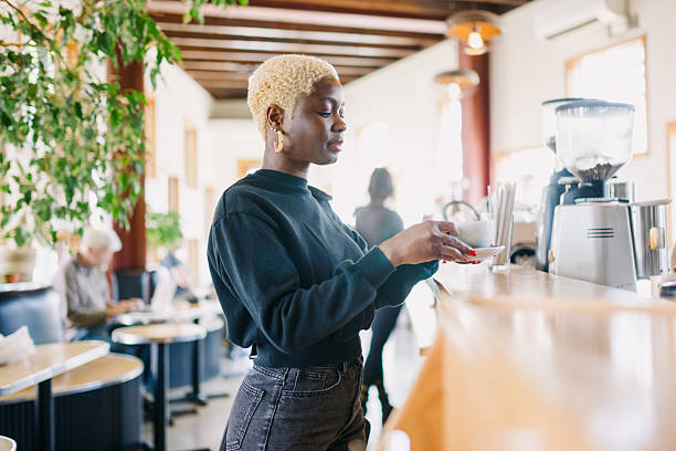 An African American woman enjoys a fresh single origin espresso latte in her favorite coffee shop.  Shot in Portland, Oregon.