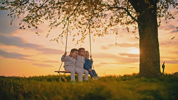 A little girl swings high on a wooden swing on a cloudy day.