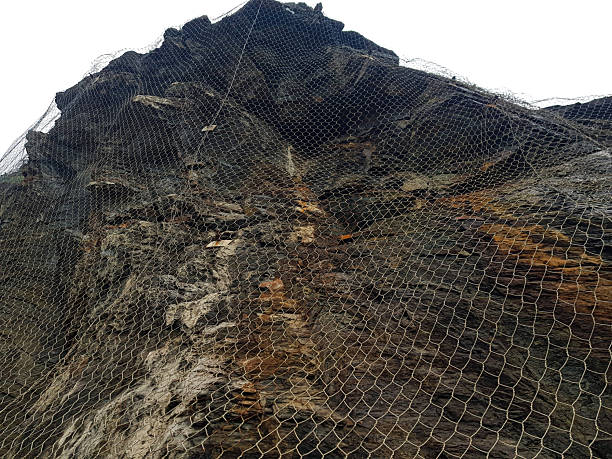 istock A towering rock face is covered with protective netting to mitigate the risk of falling rocks. This safety measure is likely installed along a popular hiking trail in a mountainous area 2212804509