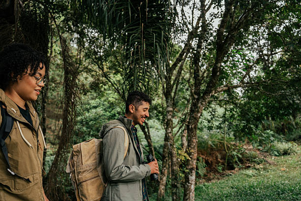 Young couple explores forest trail watching birds with binoculars