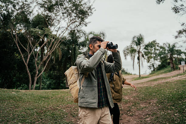 istock Young couple hiking in the forest and watching birds through binoculars 2212808230