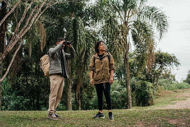 istock Young couple hiking in the forest and watching birds through binoculars 2212808232