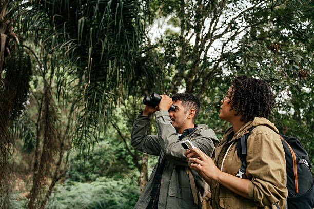 istock Young couple hiking in the forest and watching birds through binoculars 2212808237