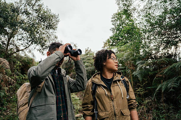 istock Young couple hiking in the forest and watching birds through binoculars 2212808247
