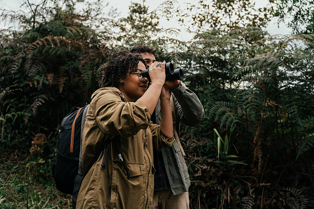 istock Young couple hiking in the forest and watching birds through binoculars 2212808252