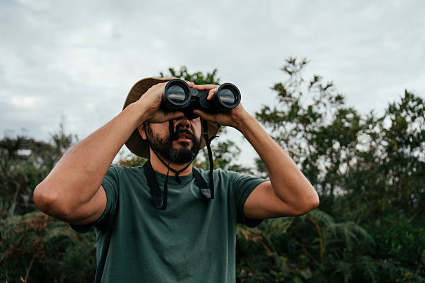 istock Adventurous man walking in forest and watching birds with binoculars 2212808280