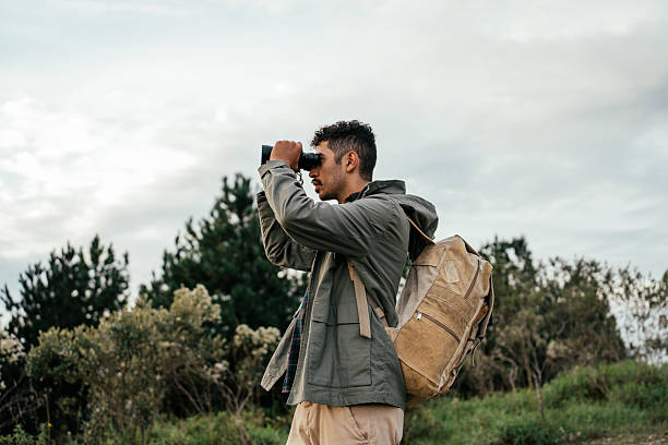 istock Young man walking in forest and watching birds with binoculars 2212808290