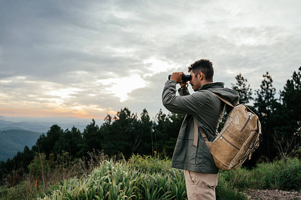 Mature man looking at view with a binoculars outdoors