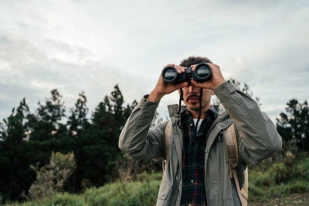 istock Young man walking in forest and watching birds with binoculars 2212808292