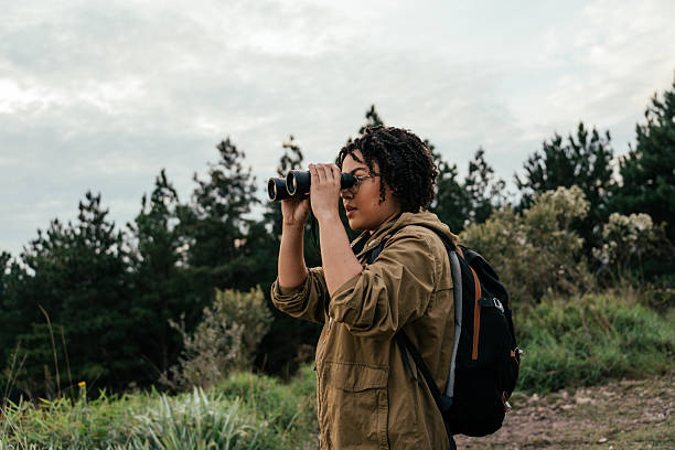 istock Young woman watching birds with binoculars in the forest 2212808293