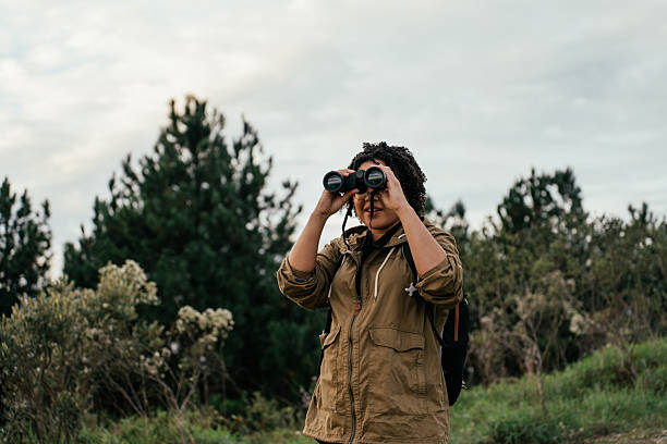 istock Young woman watching birds with binoculars in the forest 2212808294