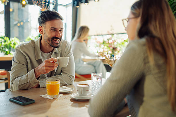 young couple enjoying coffee and conversation at a cafe - 会話 カップル ストックフォトと画像