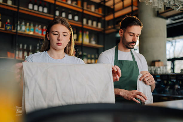 istock Two young baristas cleaning and setting up tables in a modern cafe 2212809289