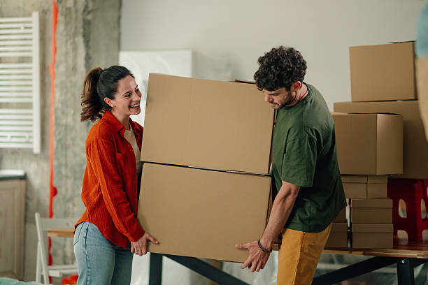istock Young couple carrying heavy cardboard boxes into new apartment 2212811389