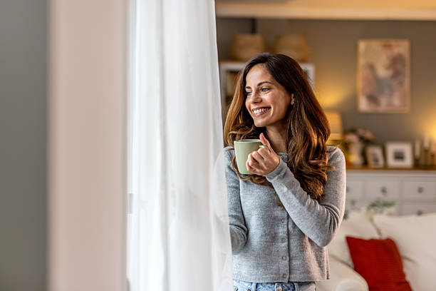 istock Smiling Woman Relaxing With Coffee While Looking Out Home Window 2212812179