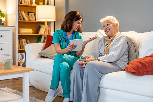istock Friendly Caregiver Interacting With Elderly Patient in Comfortable Home Setting 2212812236
