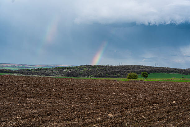 istock Spring Rainbow Over Plowed Agricultural Field 2212812636