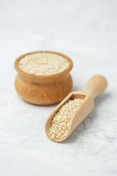istock Sesame seeds in a wooden scoop and container on a light background 2212813166