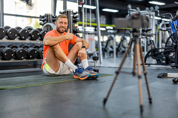 istock Smiling Coach Filming Fitness Tutorial Inside a Gym with Equipment 2212814720